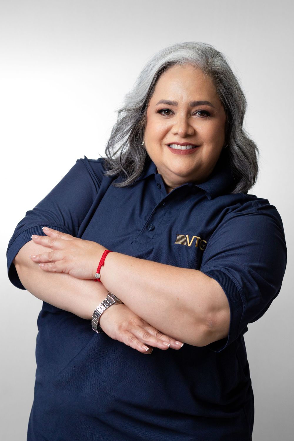 Professional studio portraits show a person with silver hair in a navy polo shirt posing with crossed arms against gray backdrop.