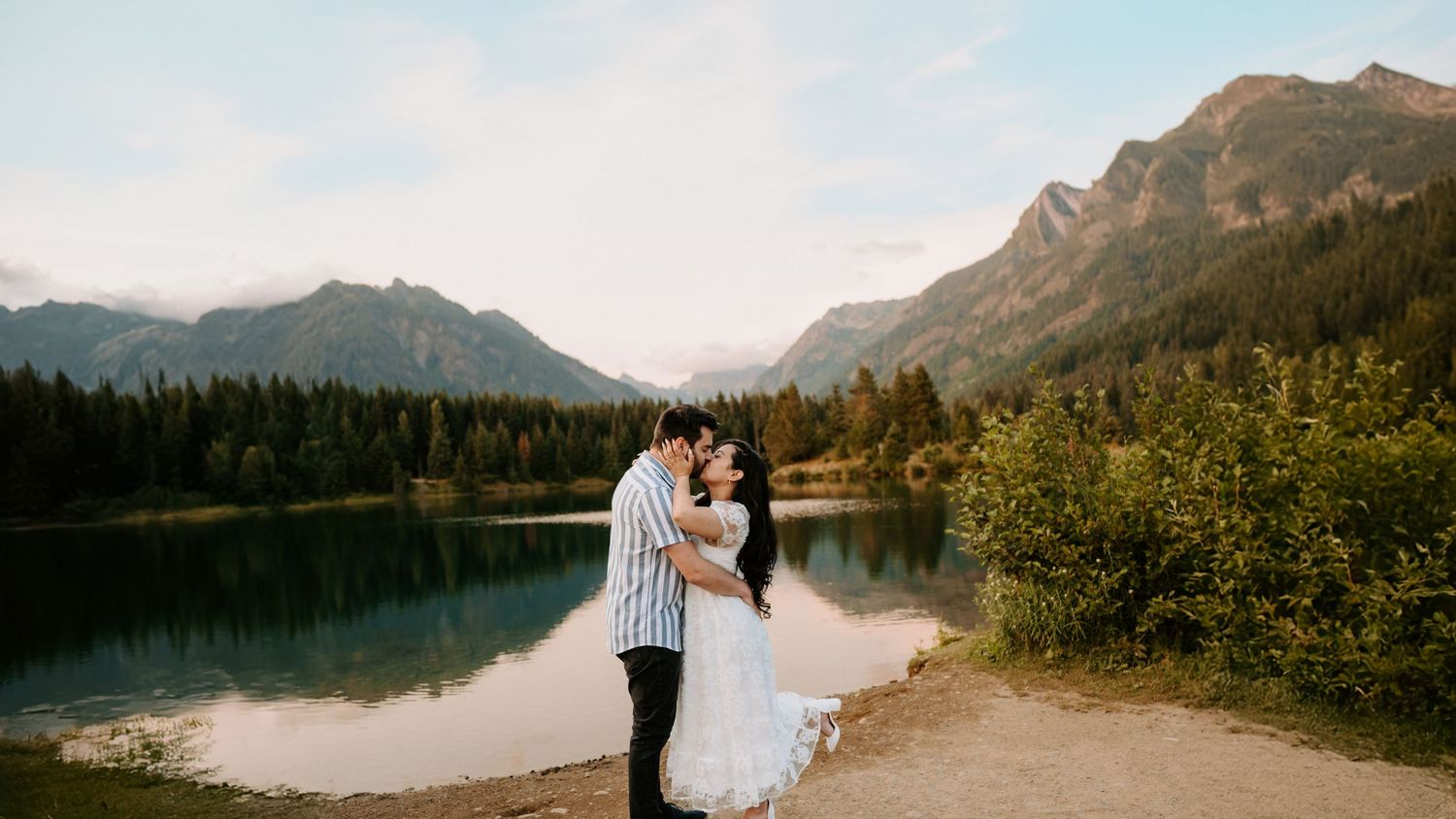 Scenic mountain lake view with snow-capped peaks and evergreen forest.