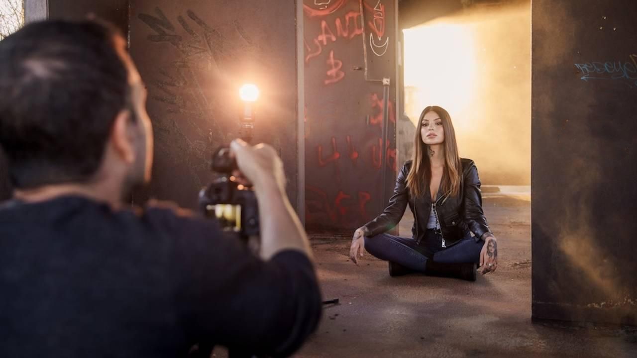 Behind-the-scenes photo shoot of a yoga meditation pose in an atmospheric industrial setting with dramatic lighting.