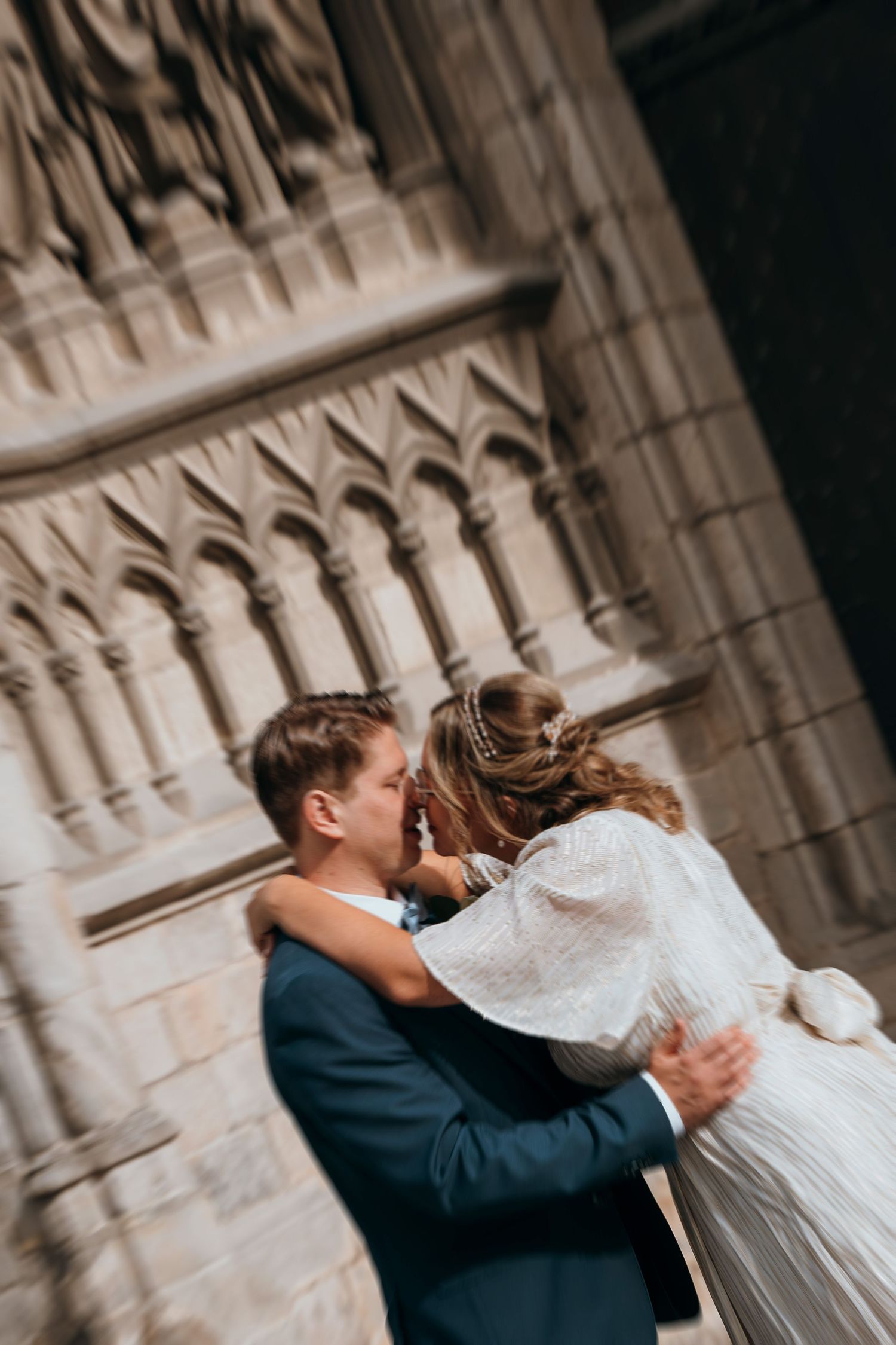 An intimate wedding embrace captured against the backdrop of Gothic stone architecture.