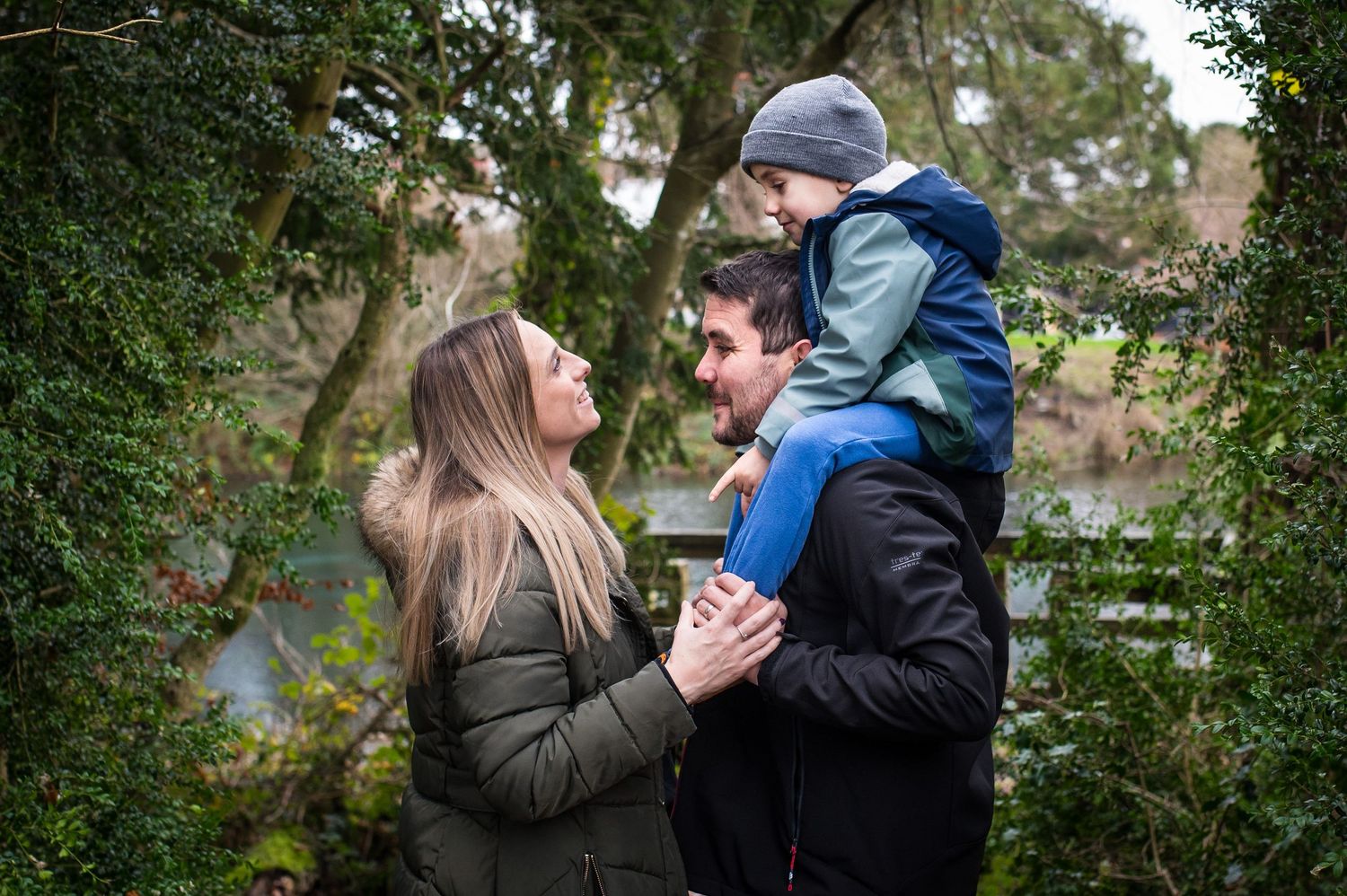 5 year old sitting on dads shoulders during an autumn mini shoot, whilst he looks lovingly at his mum.