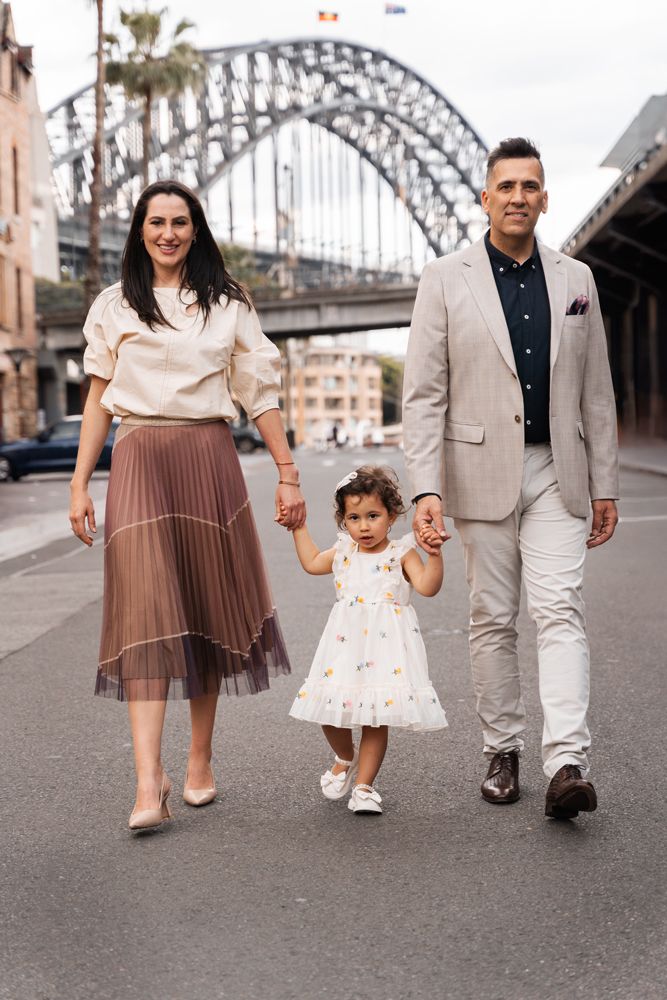 Family walks through the city streets with the iconic Harbour Bridge in the background during a family photoshoot