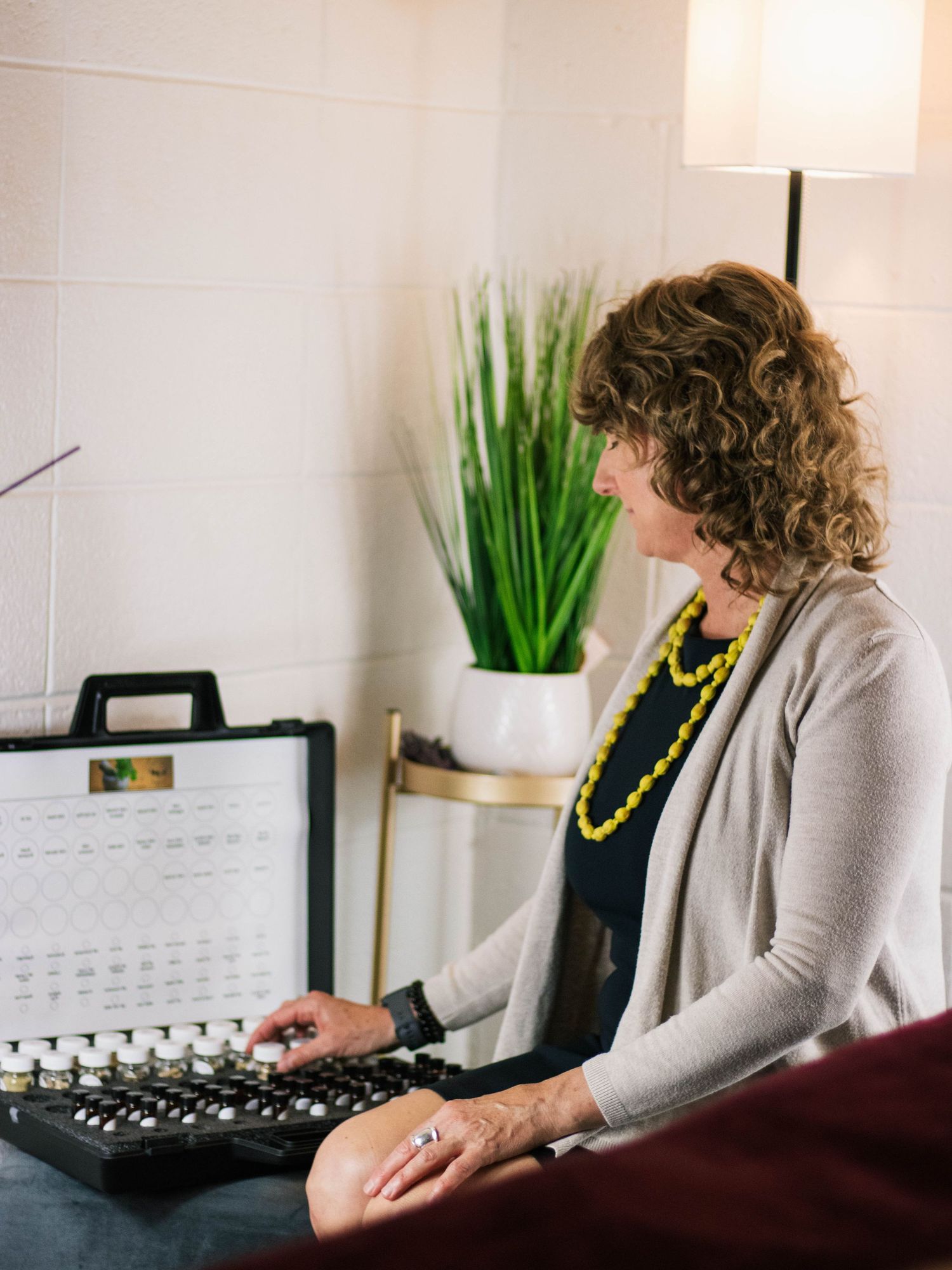 Side view of person working at desk with computer equipment and decorative plant.