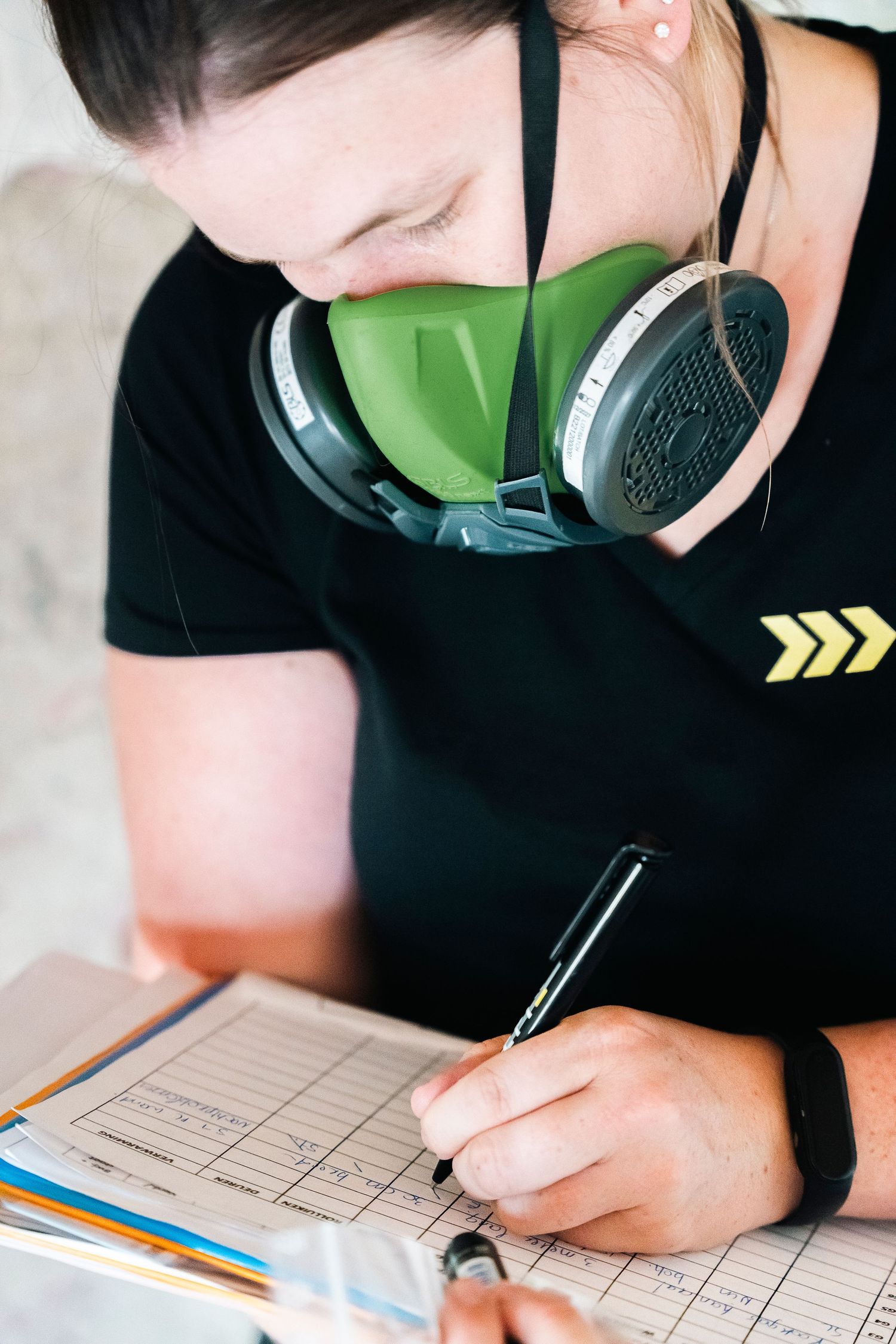 Professional wearing protective mask making notes on a document during investigation.