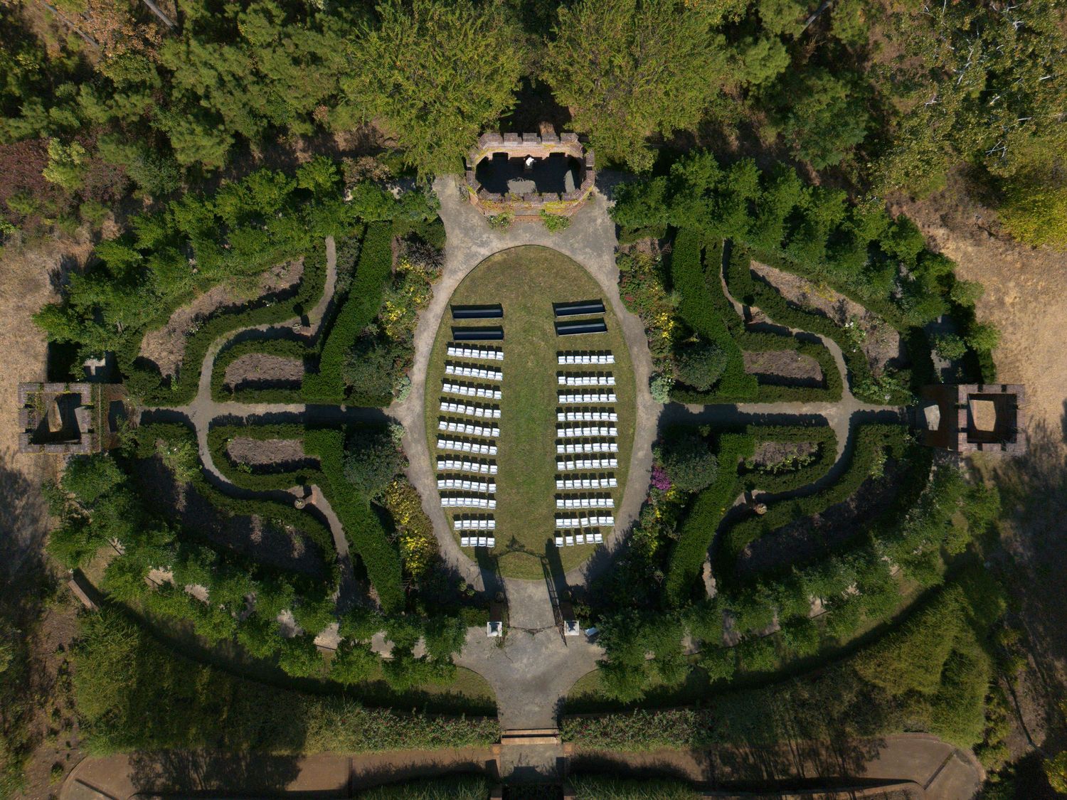 Aerial drone shot of a manicured garden venue with curved pathways and seating areas.