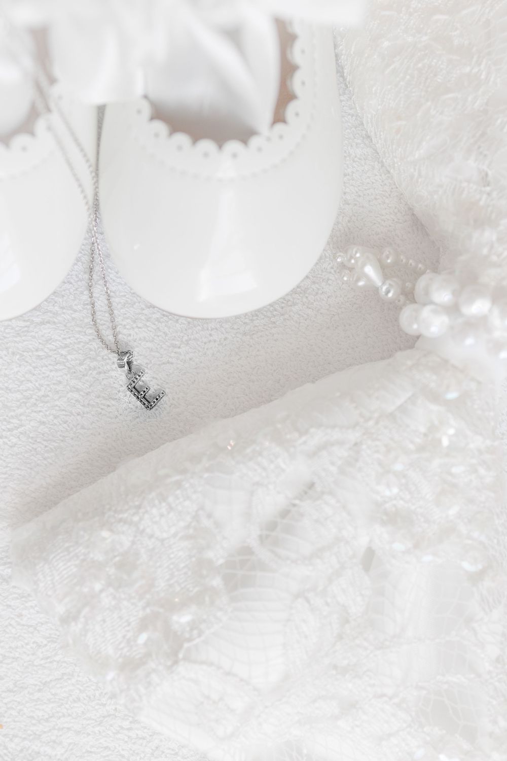 Delicate silver necklace with small pendant laying on white lace fabric with soft lighting.