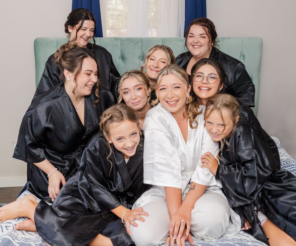 Bridal party wearing matching black silk robes posing together on couch.