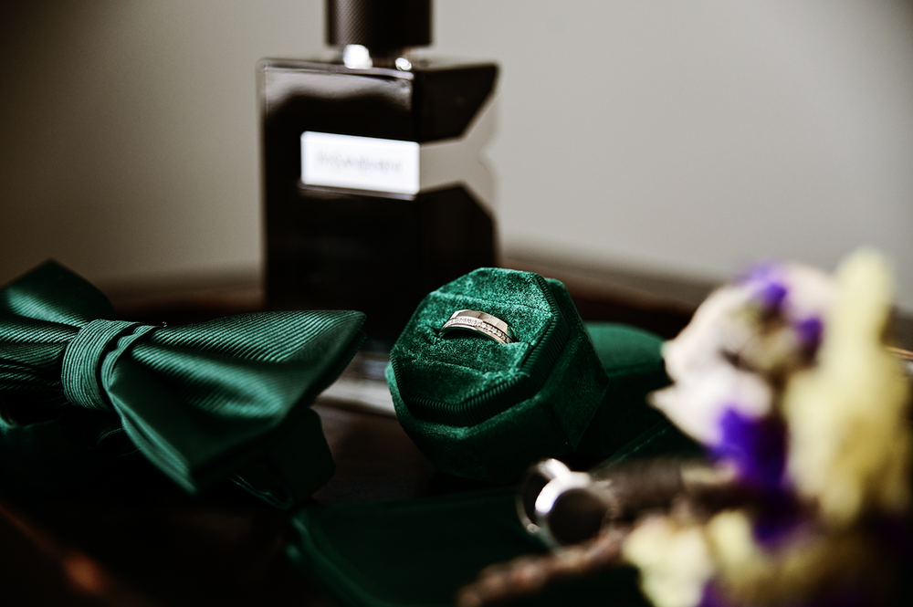 Emerald green bow ties and floral accessories arranged on dark surface.