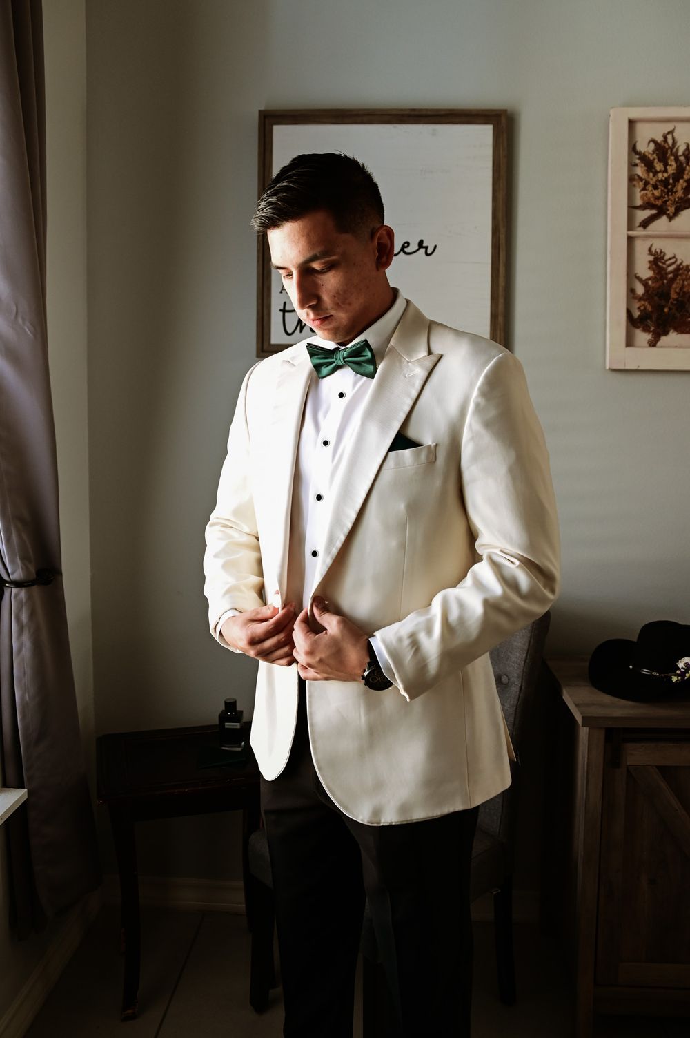 Groom in white dinner jacket and bow tie preparing for wedding ceremony.