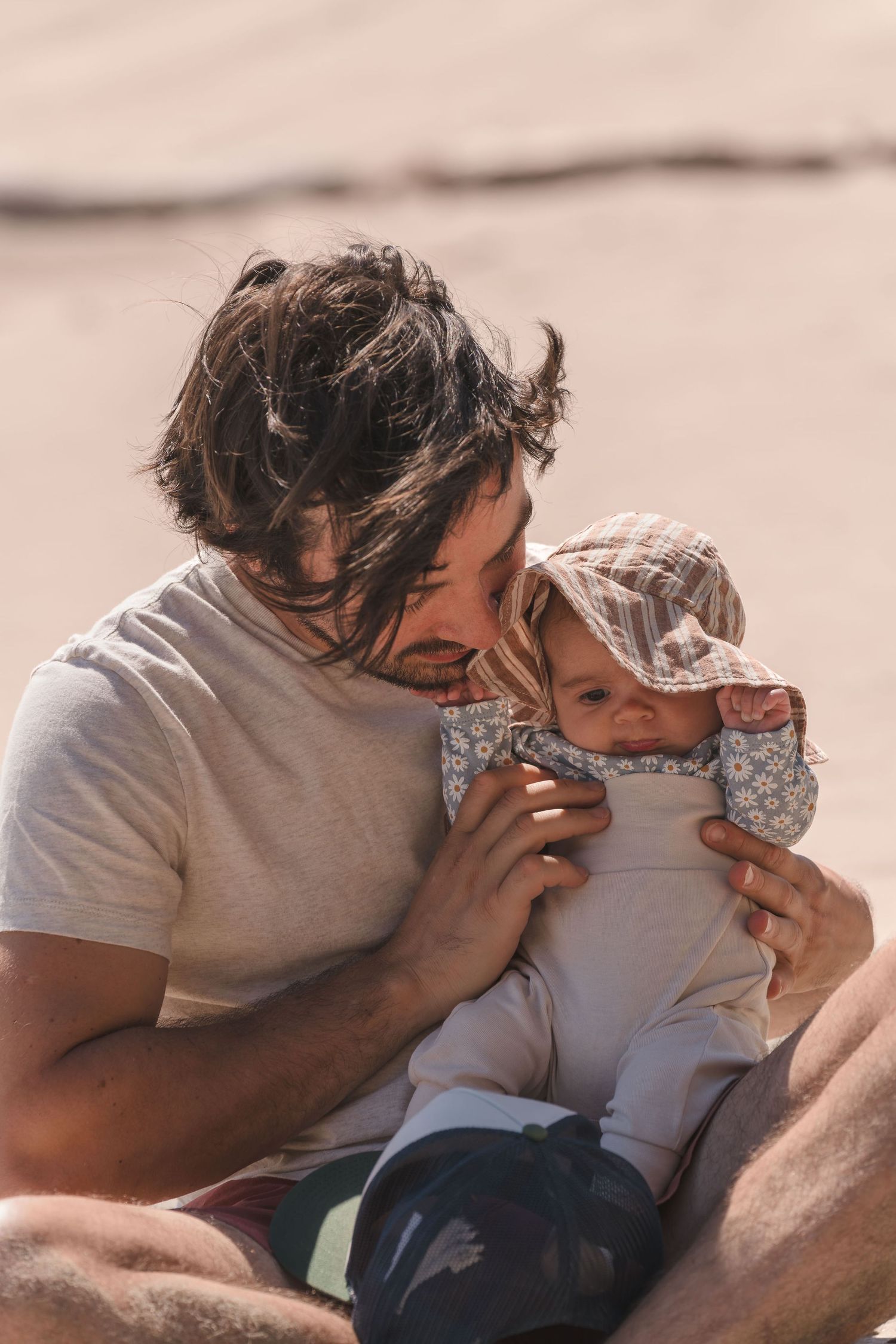 Intimate family moment shared on sunny beach during golden hour. Located near Santa Cruz, CA.