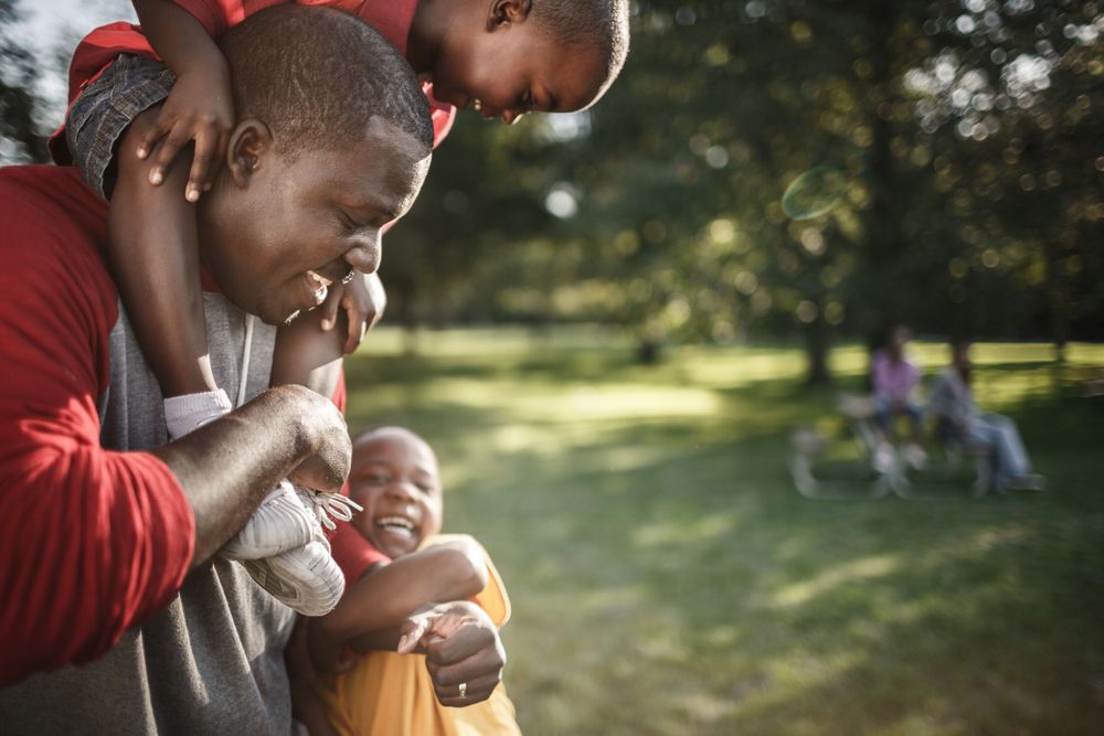 A tender family moment outdoors in a park on a sunny day.