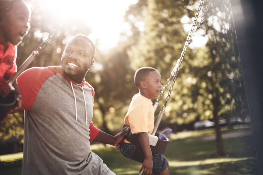 A family enjoying outdoor playtime in a park during golden hour sunlight.
