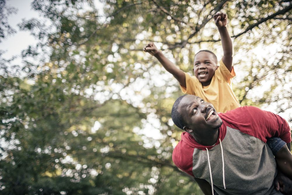 Playful piggyback ride moment in a sunlit park.