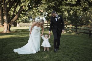 Wedding party walks together across a sunlit lawn during outdoor ceremony.