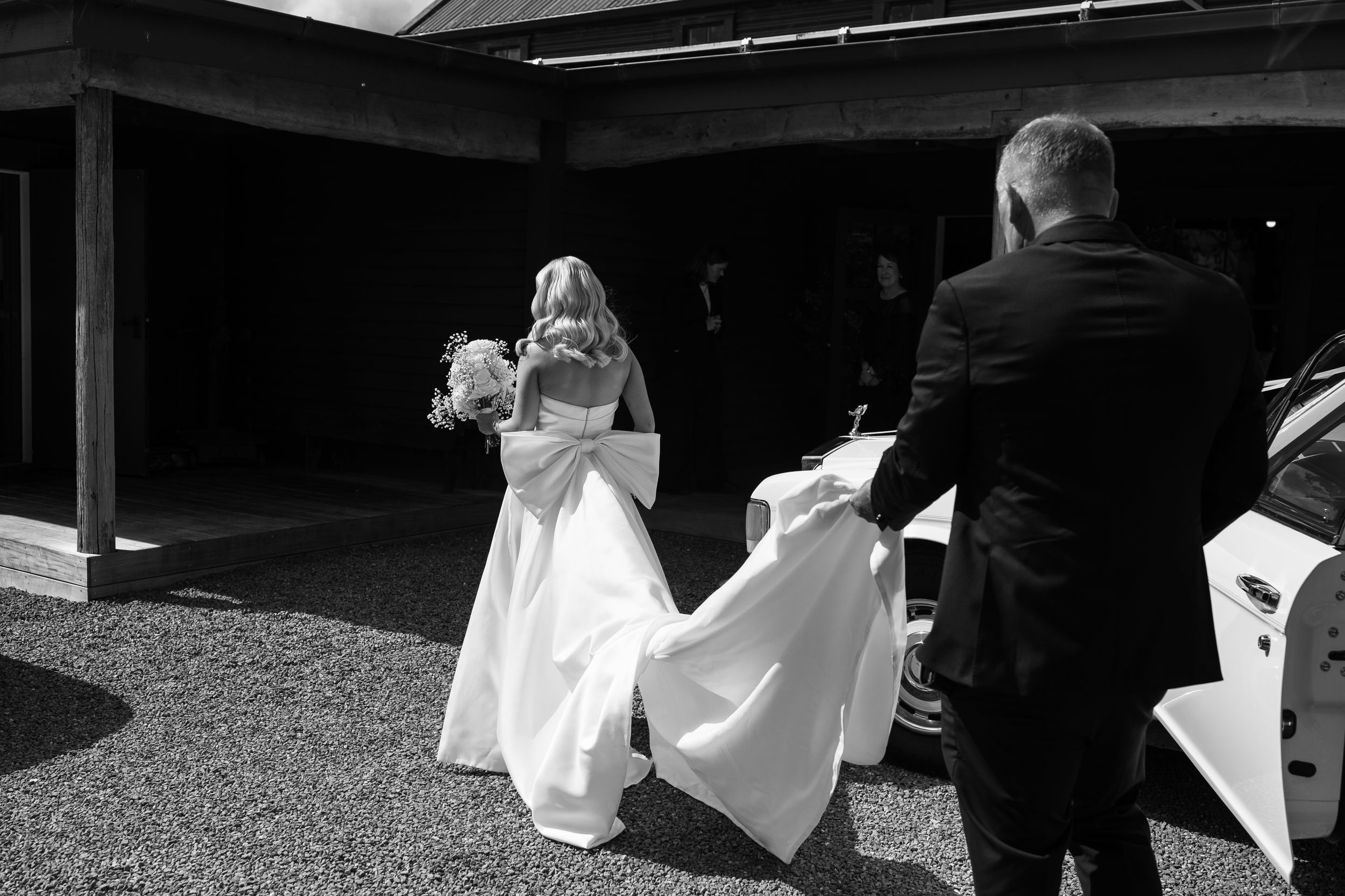 Wedding party exits venue in dramatic black and white sequence shot.