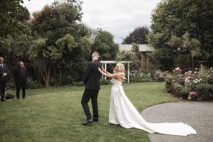 Couple dancing together on garden lawn during wedding celebration.