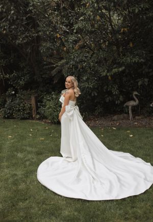 Elegant wedding dress with dramatic train photographed in garden setting.