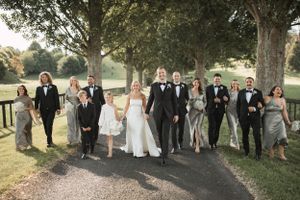 Wedding party and guests posed for formal portraits under mature trees.