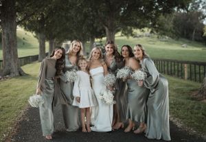 Wedding party in coordinated grey and white attire gathered for outdoor group photos.