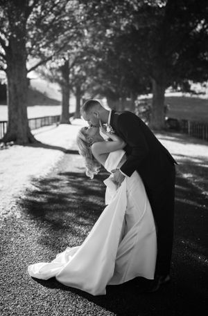 Black and white photos capture romantic dip pose sequence on gravel pathway.