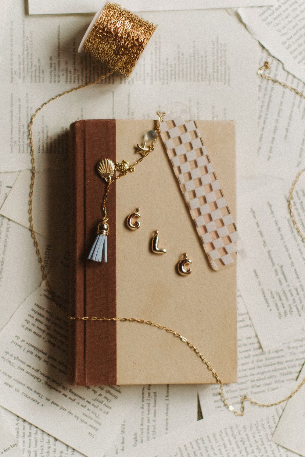 A vintage-style book with gold moon decorations, tassels, and gold string on a cream colored background.