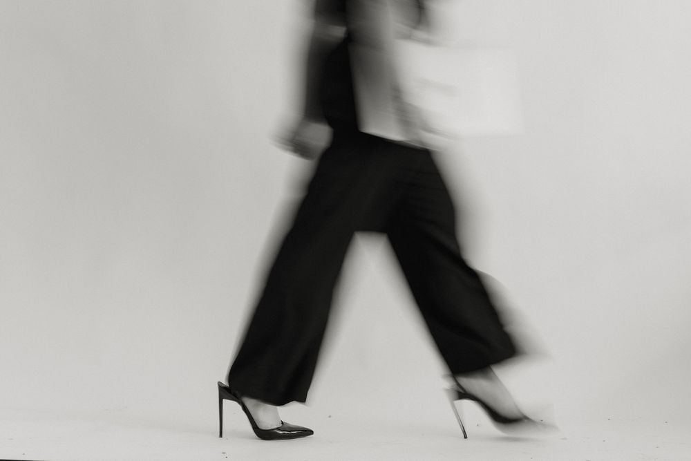 A series of black and white photographs showing legs walking in high heels arranged in a filmstrip-like sequence.