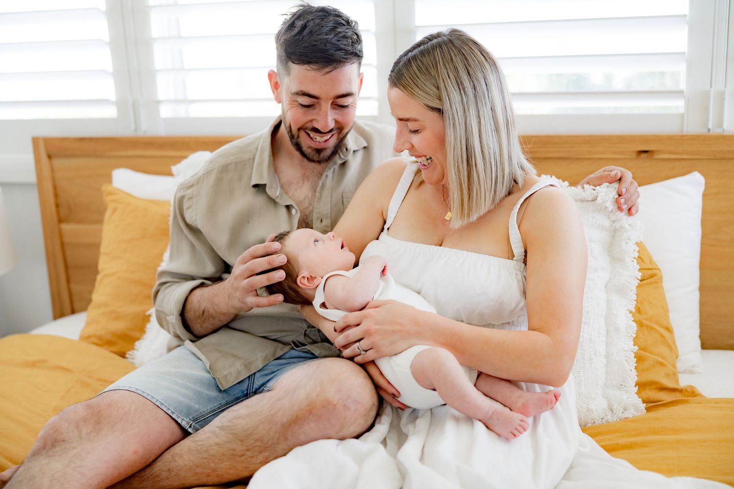 Parents sharing a tender moment with their baby on a yellow bed.