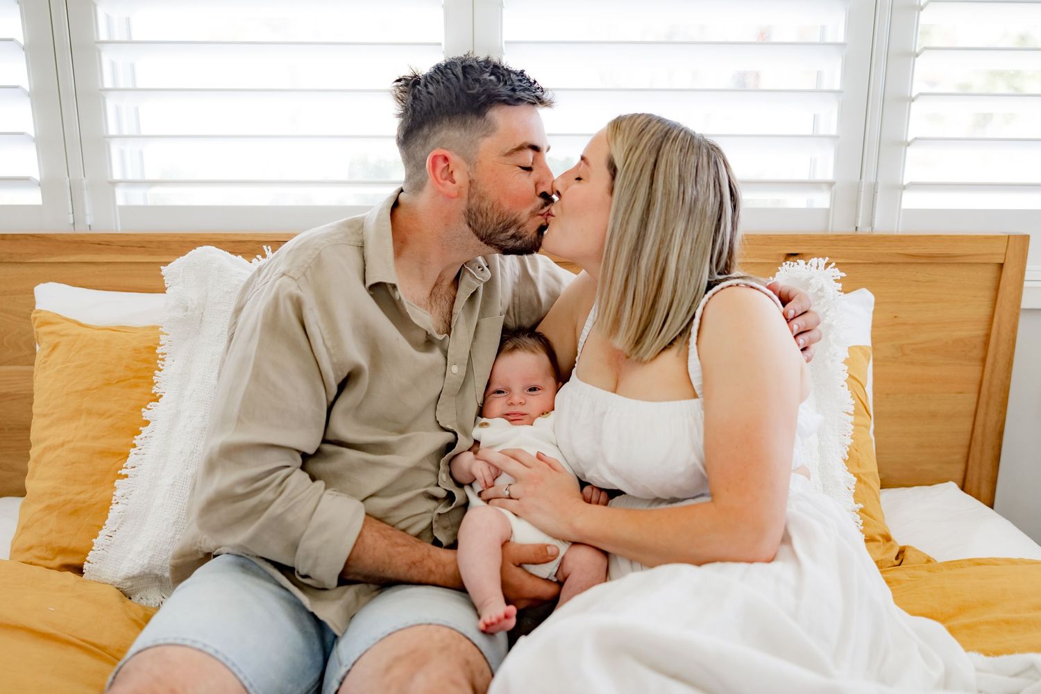 An intimate family moment shared on a bed with yellow pillows.