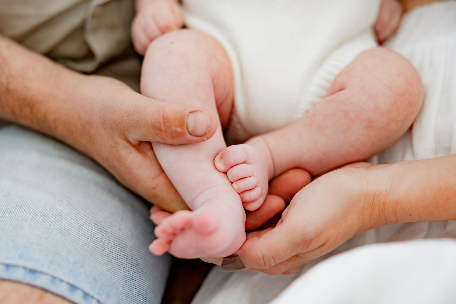 Close-up of tiny baby feet being held by adult hands.