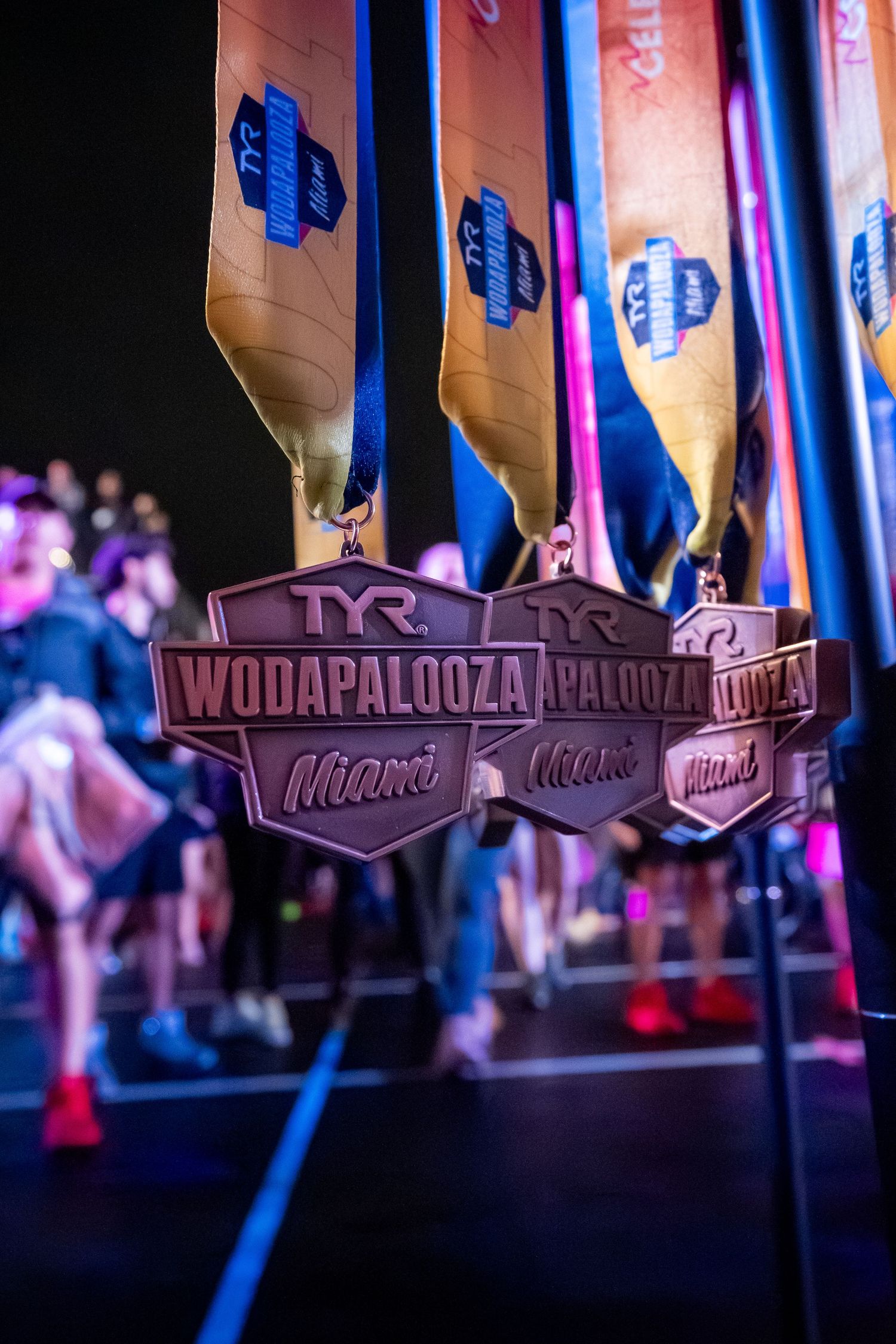 Wodapalooza fitness competition medals hanging against dark background.