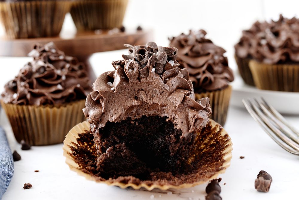 Chocolate cupcake with bite taken out showing moist interior and chocolate frosting.