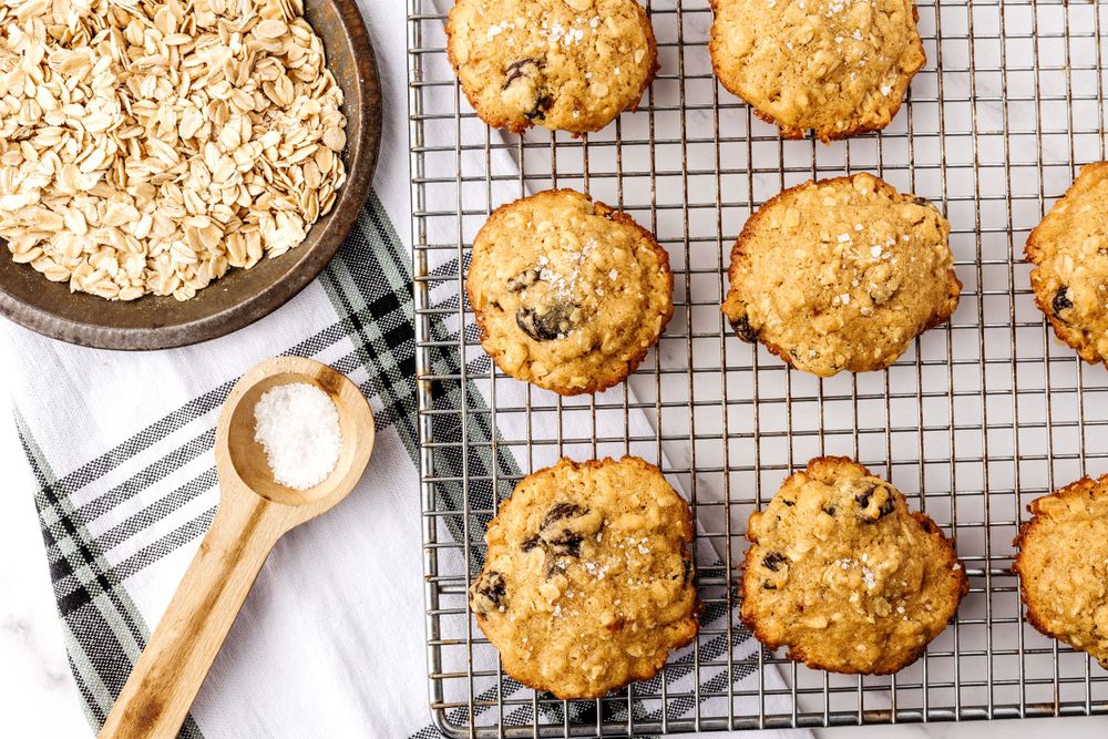 Fresh baked oatmeal chocolate chip cookies cooling on a wire rack with ingredients nearby.