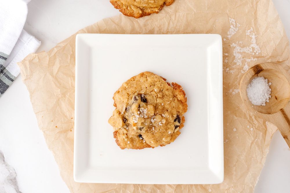 Homemade chocolate chip cookie on a white square plate with parchment paper.