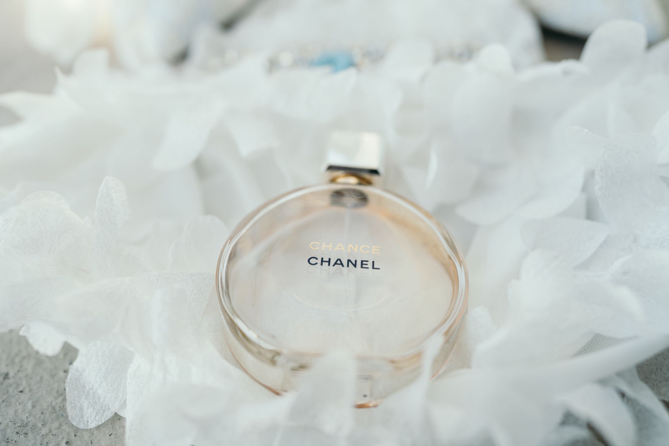 Chanel ring photographed on delicate white fabric with soft lighting.