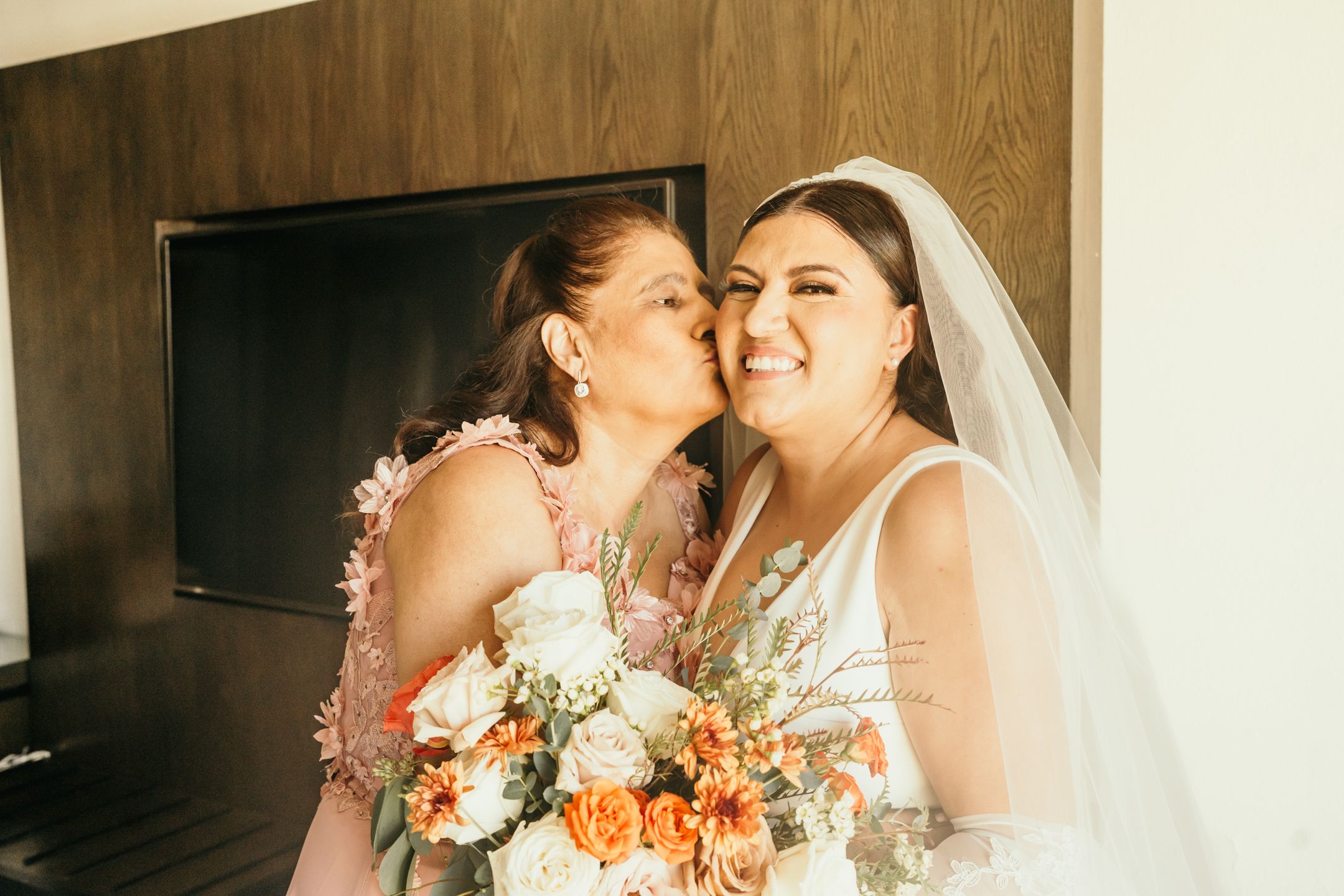 Two people in wedding attire share a joyful moment with colorful bouquets of flowers.
