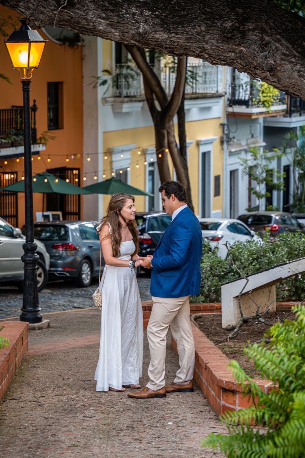A couple shares a tender moment on a charming Old San Juan street with colorful buildings.