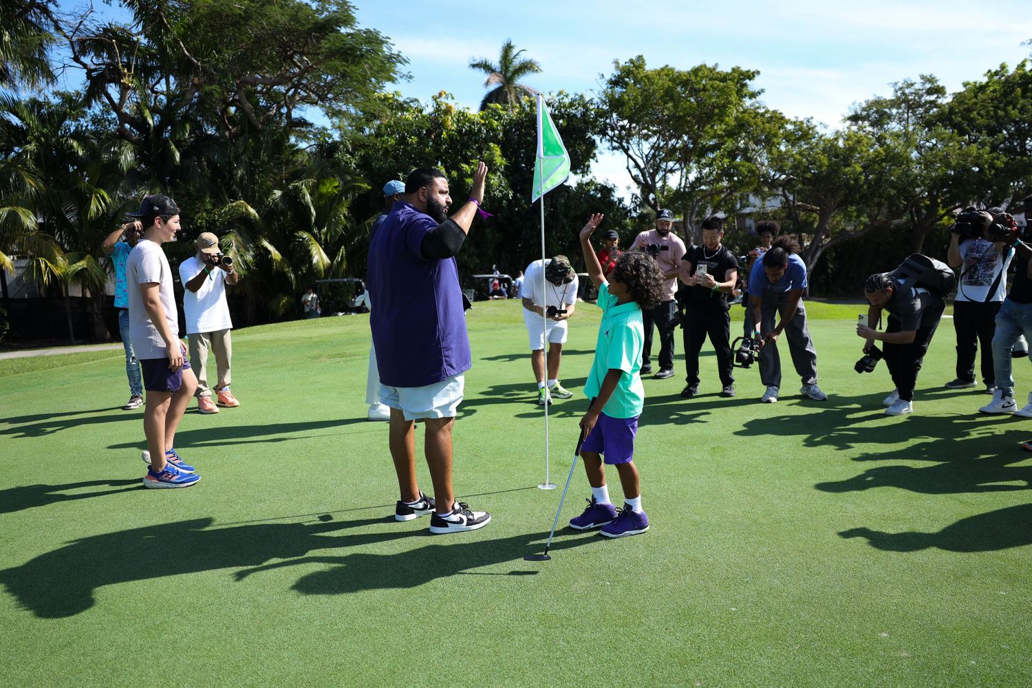 Golf instruction taking place on a putting green with a group of students and an instructor holding a flag.