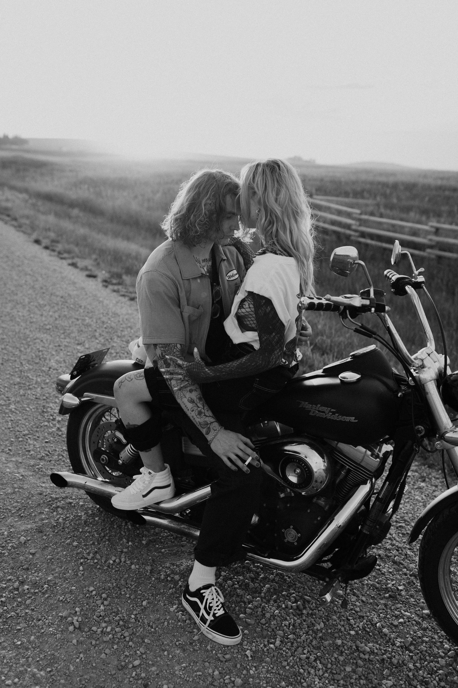 Romantic couple sharing intimate moment on motorcycle on rural road.