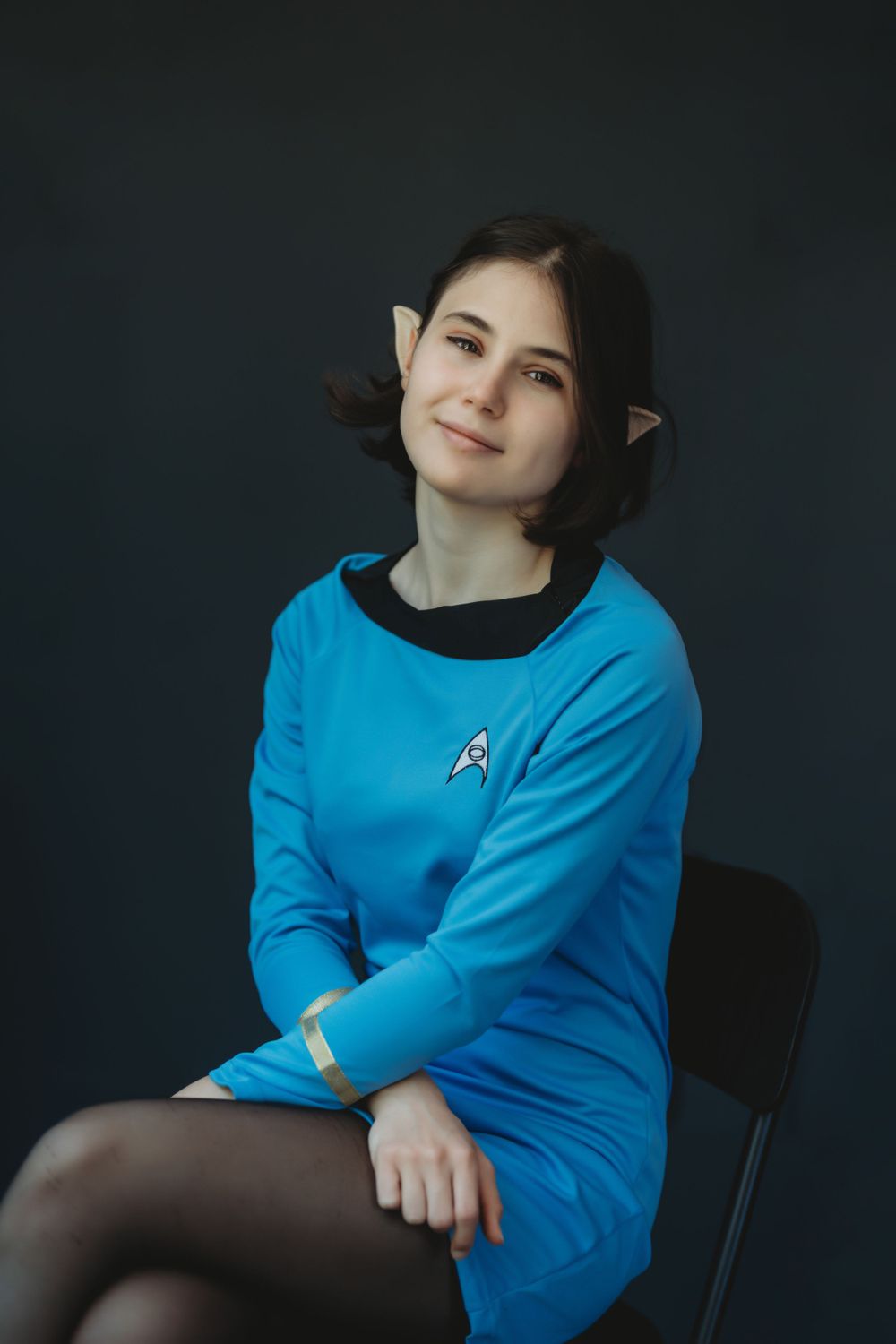 A person wearing a Star Trek-inspired blue uniform poses against a dark background. Bellevue studio, WA