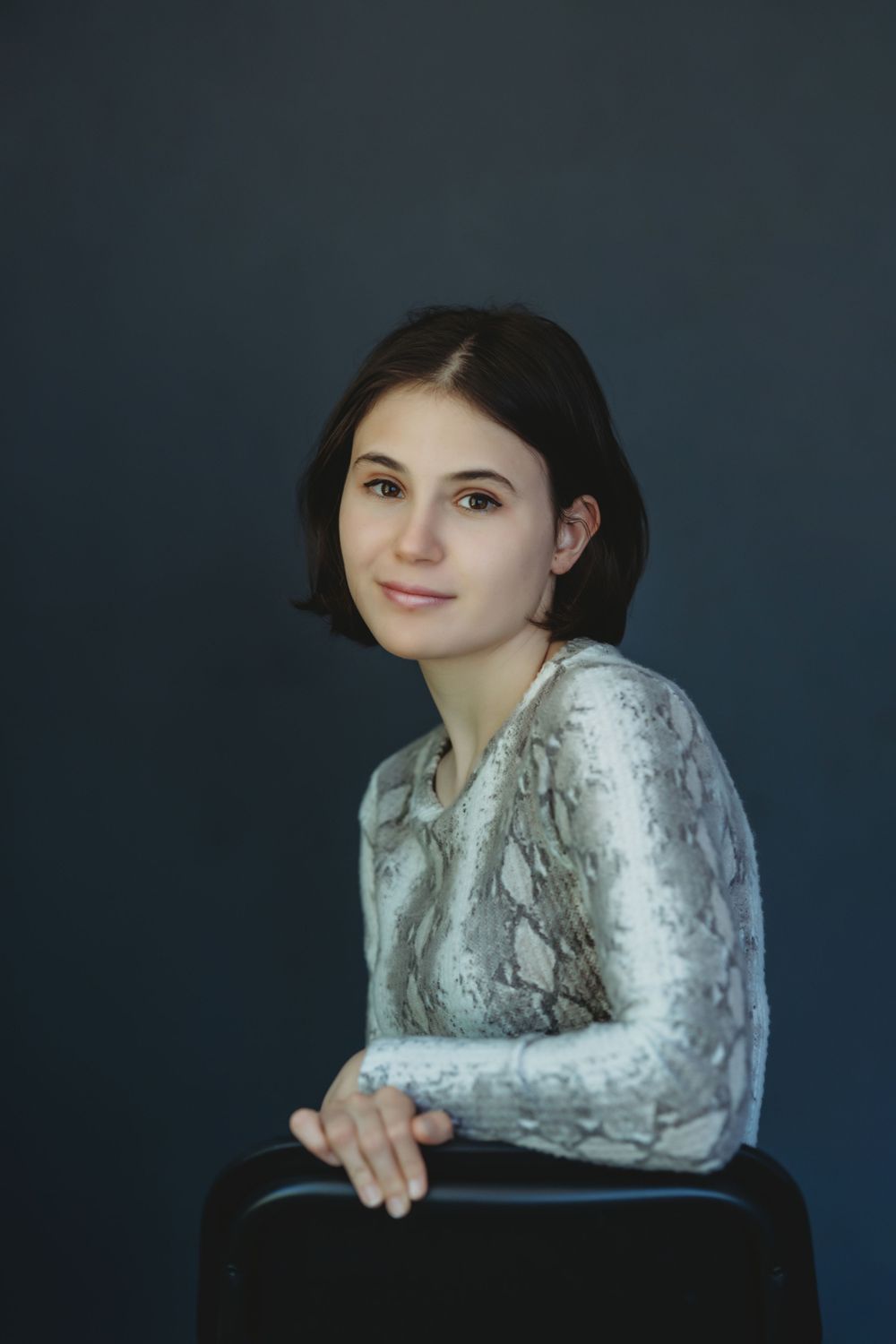 Classic studio portrait featuring textured blouse against dark backdrop. Bellevue studio, WA
