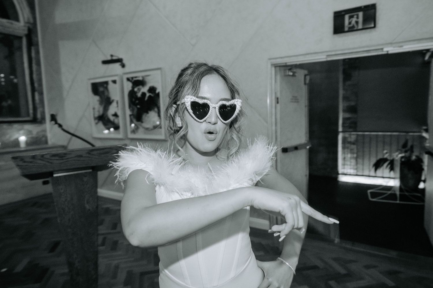 Black and white photo of bride in sunglasses making playful pose.