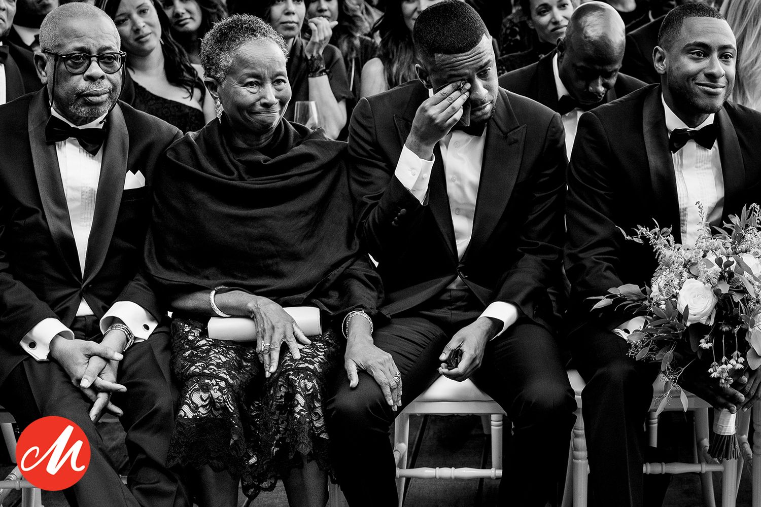 Formal event with attendees seated in rows wearing black tie attire.