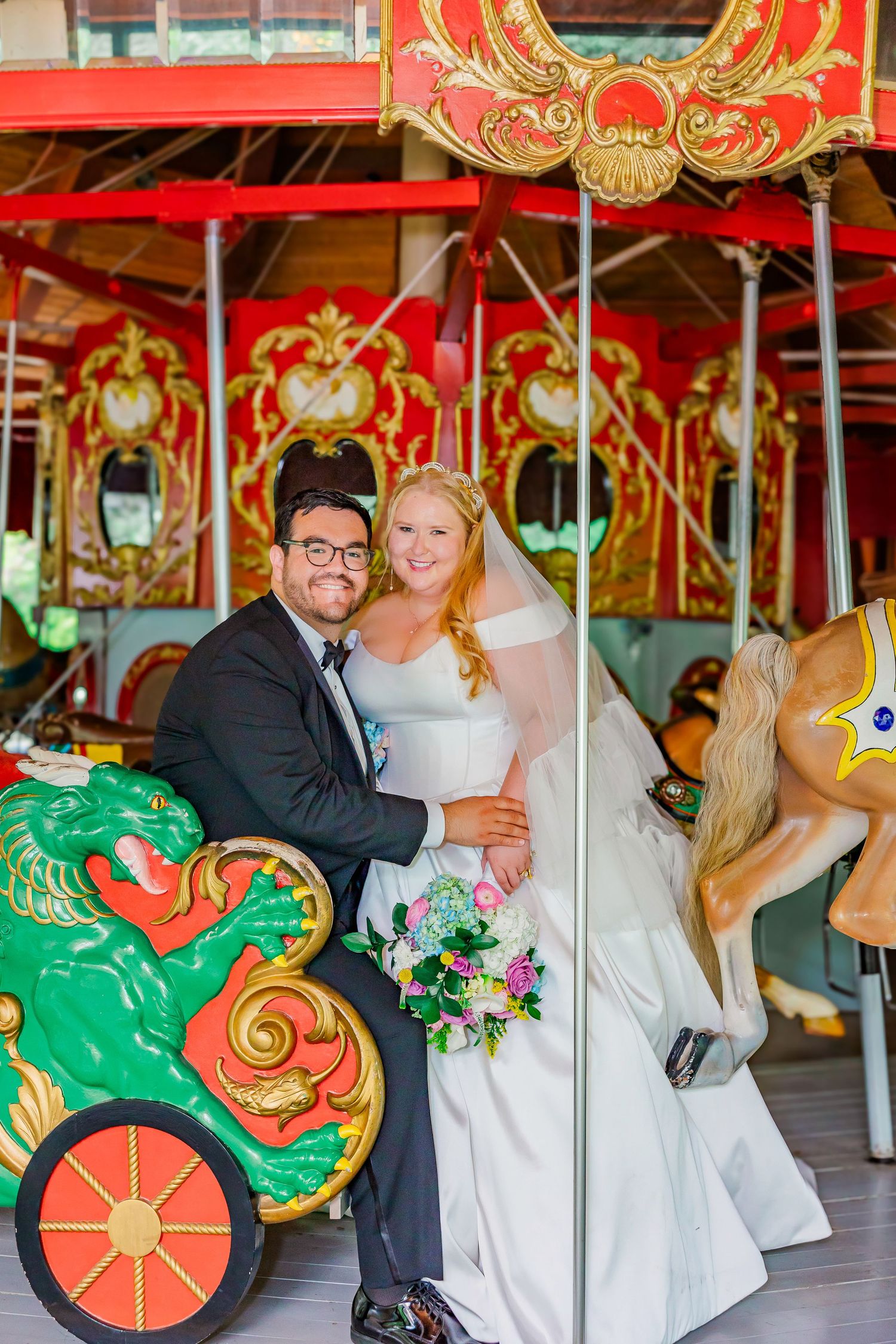 Romantic carousel photoshoot featuring elegant wedding attire and colorfully decorated vintage carnival horses.