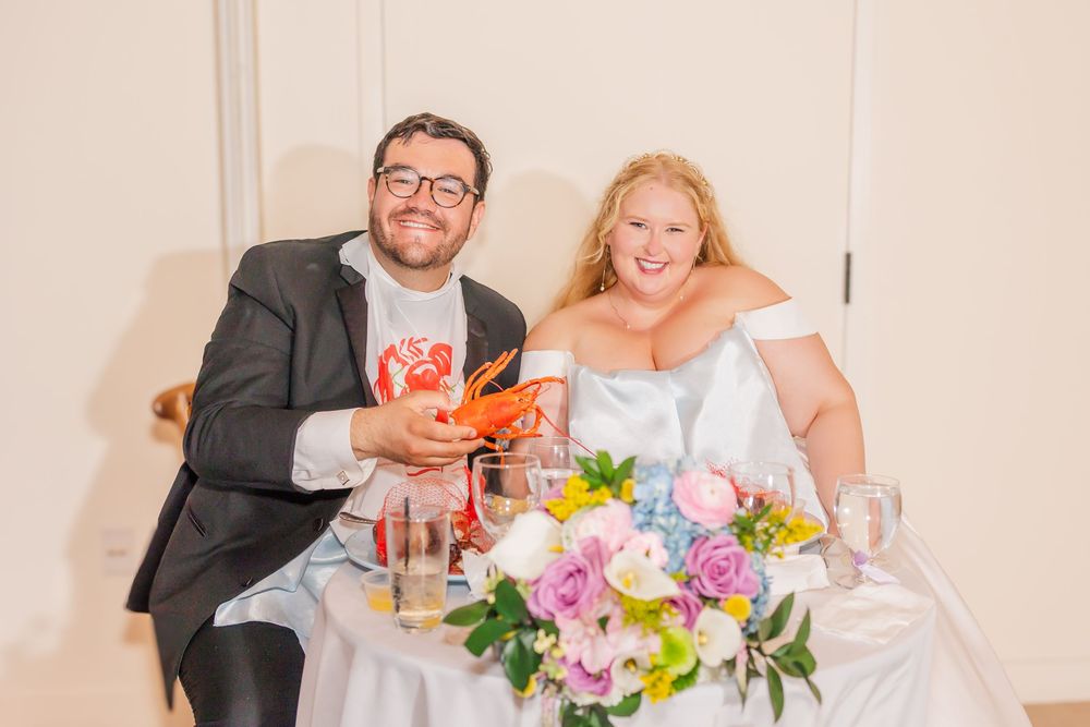 Wedding reception guests laughing and toasting with colorful cocktails at a decorated table.