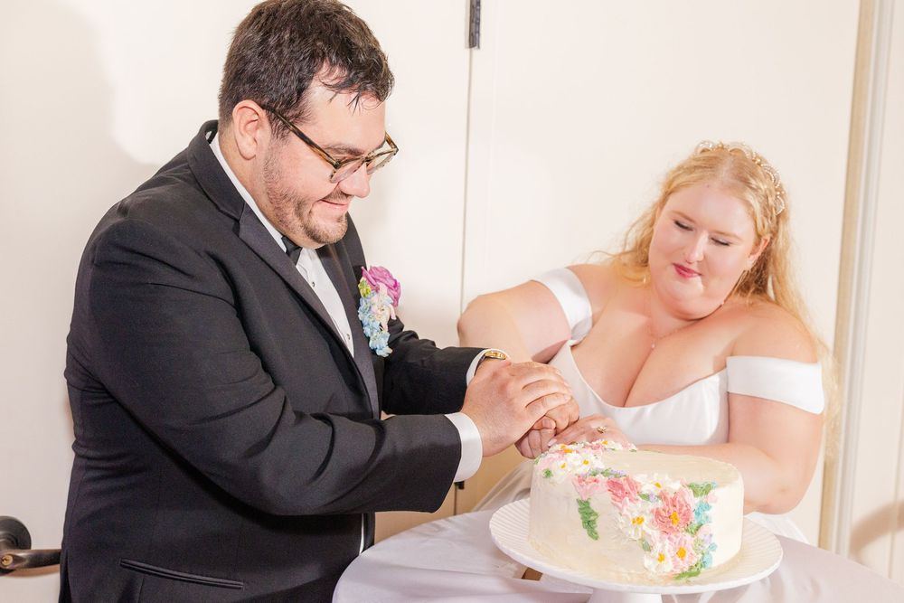 Newlyweds sharing cake at their wedding reception with joyful expressions.