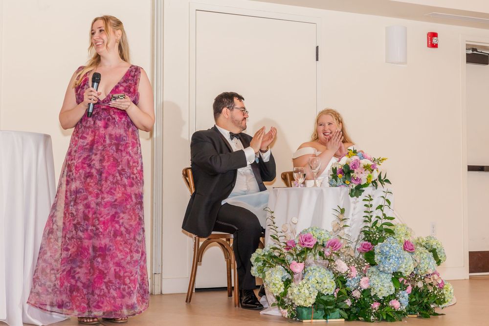 Wedding reception venue decorated with pink and white floral arrangements and white tablecloths.