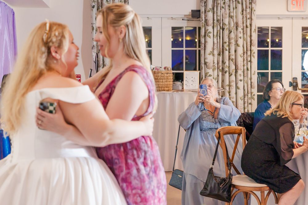 Wedding reception guests dancing and celebrating together in a banquet hall with floral curtains.