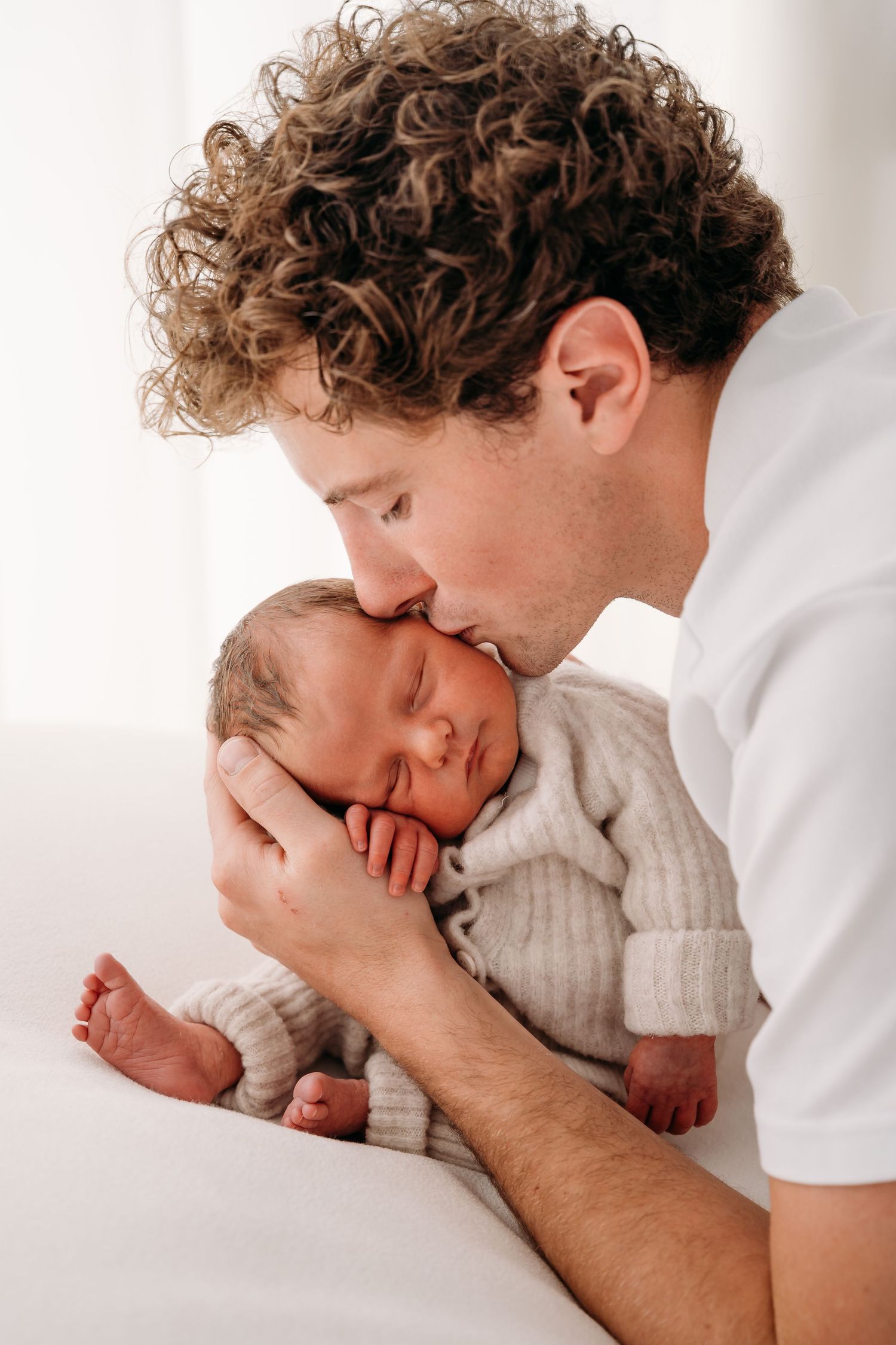 Newborn met zijn papa tijdens een newbornshoot in een daglichtstudio in Edegem.
