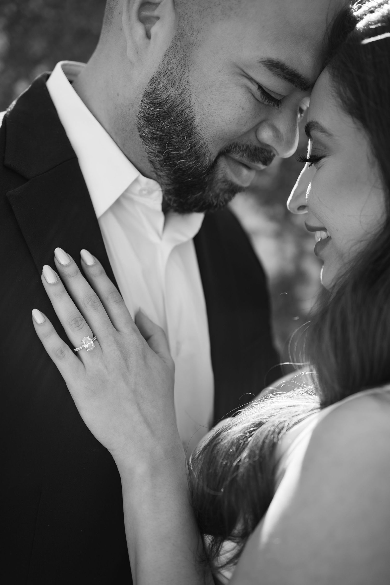 Elegant couple in formal black attire poses together in a romantic outdoor photoshoot series.