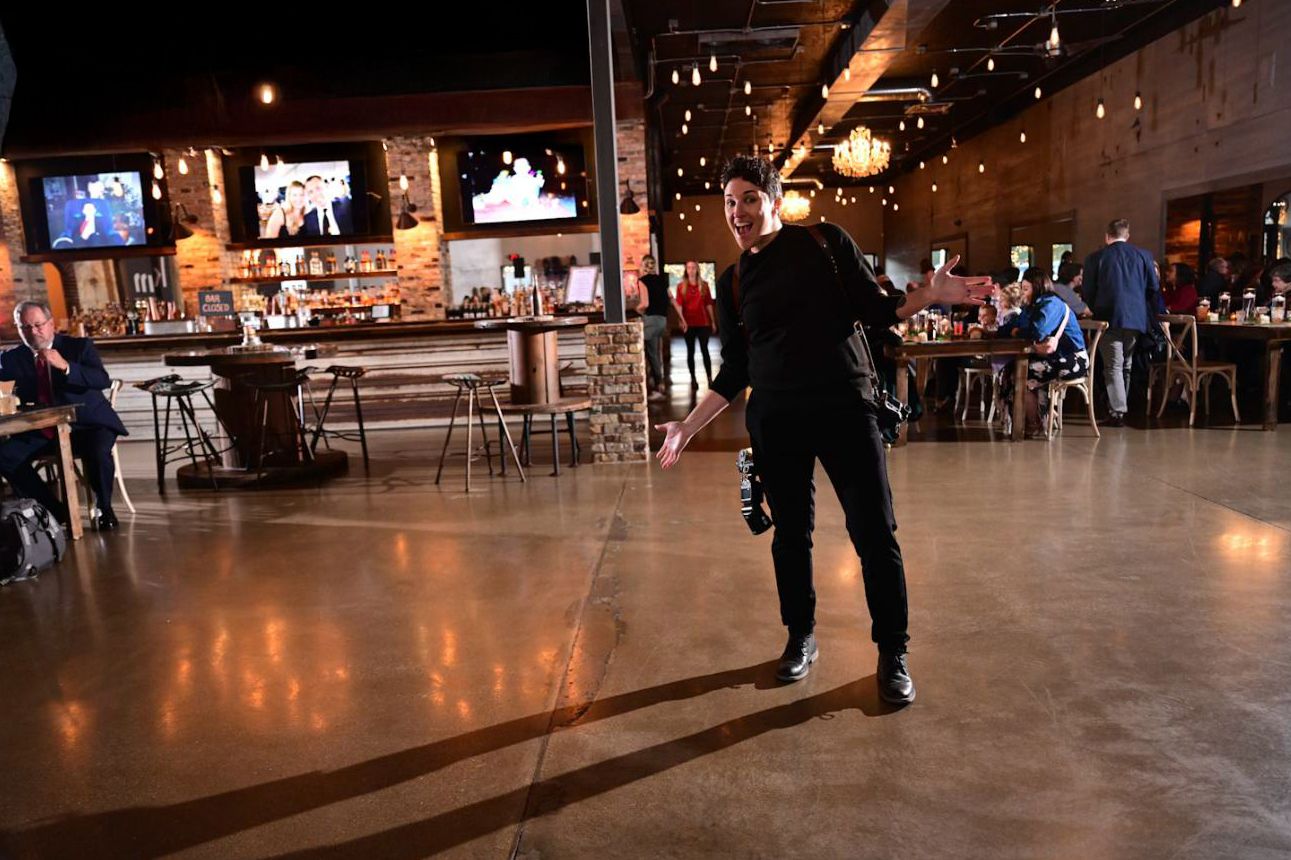 Skaters glide across a wooden roller rink floor illuminated by warm overhead lights in an indoor entertainment venue.